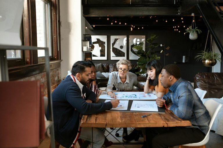 image representant le management d'equipe via plusieurs personnes assises a table entrain de discuter